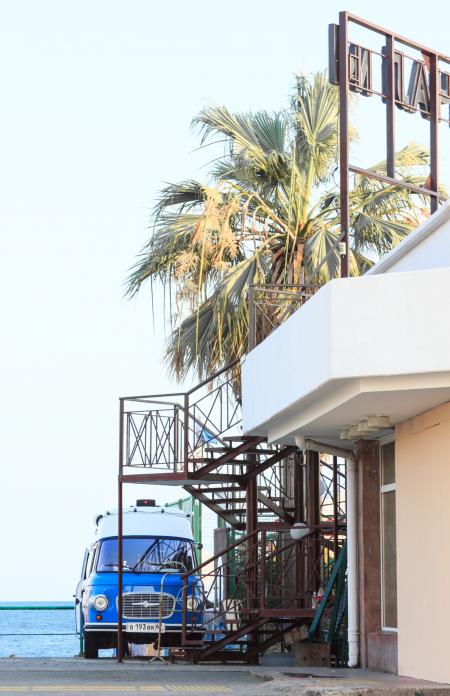 Blue Vehicle Park Near Brown Metal Outdoor Stairs and White Concrete House at Daytime