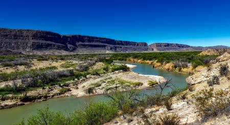 Body of Water Between 2 Mountains Under Clear Sky during Daytime