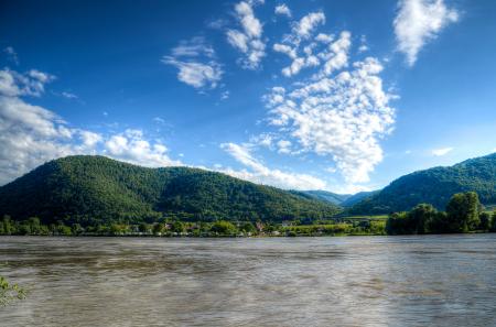 Body of Water Near Mountains Under Blue Sky