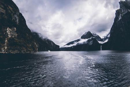 Body of Water Surround by Mountains Under Cloudy Sky