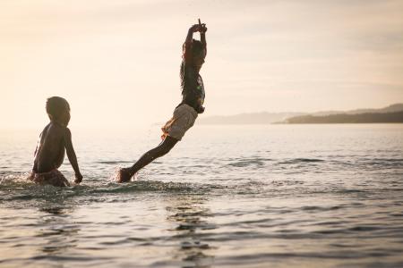 Boy Floating over Water Near Boy Standing on Side