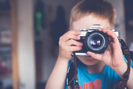 Boy in Blue Crew Neck T Shirt Taking Photo Using Minolta Dslr Camera during Daytime