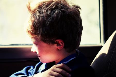 Boy in Blue Jacket Sitting Next to Vehicle Window