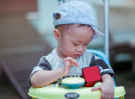 Boy in Gray Crew-neck Shirt Wearing Gray Cap Riding on Yellow and Blue Walker