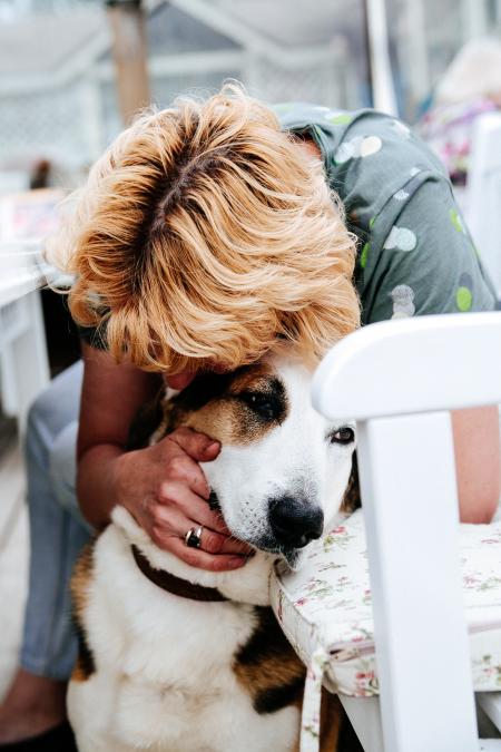 Boy in Gray Floral T-shirt Hugging White and Tan Dog