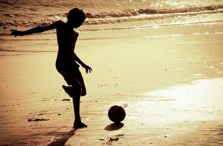 Boy on the beach playing football