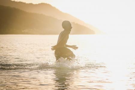 Boy Rushing Into the Body of Water during Daytime