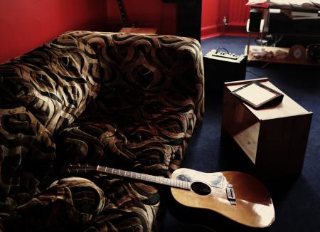 Brown Acoustic Guitar Leaning on Brown Velvet Couch