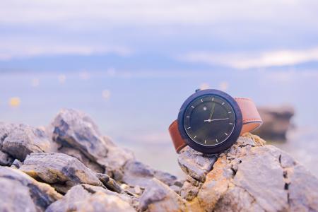 Brown and Black Round Analog Watch on Beige Rocks