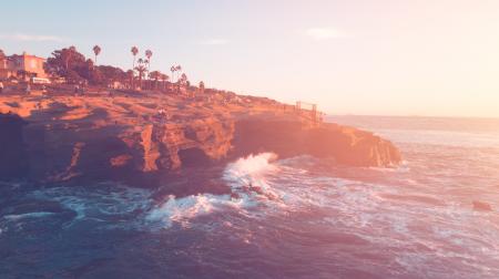 Brown Cliff Beside Ocean Under Blue Sky