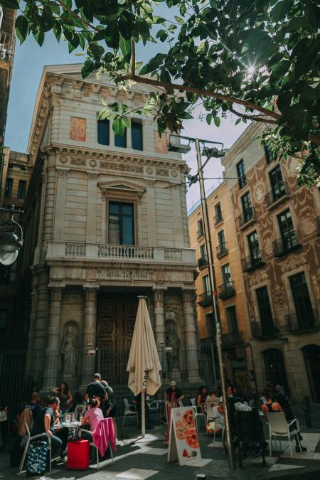 Brown Concrete Building With People Sitting on Patio Sets Photo Taken