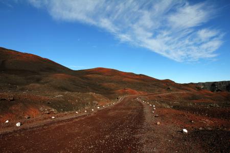 Brown Road Beside Hills over White Clouds and Blue Sky during Daytime