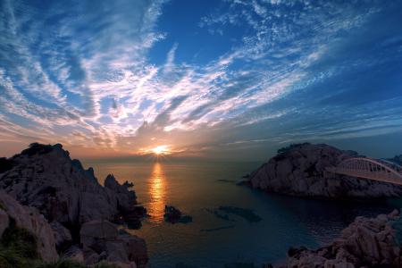 Brown Rock Formation Near Body of Water Under Blue Cloudy Sky during Sunset