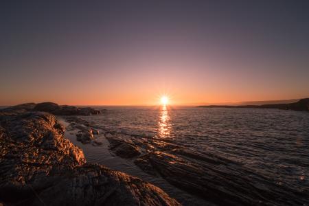 Brown Rocks Beside Body of Water during Sunset