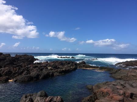 Brown Rocks Beside Ocean With Bubble Wave Under Blue Sky
