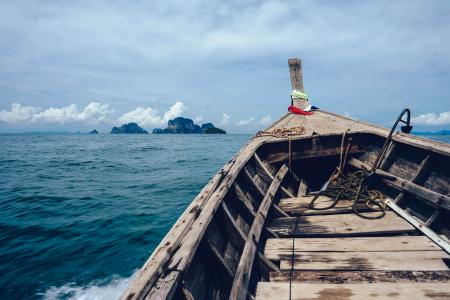 Brown Wooden Boat on Sea Overlooking Rocky Island