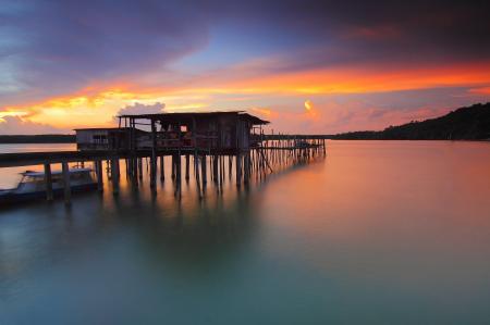 Brown Wooden Cabin Standing in the Middle of Water Besides White Boat during Nigh Time Landscape