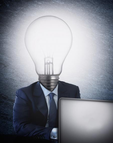 Businessman with lightbulb head in front of the computer
