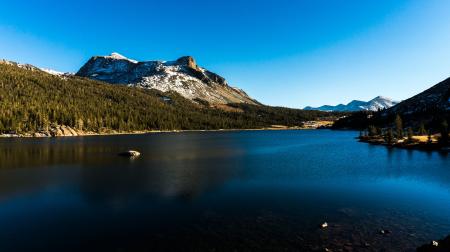 Calm Water Near Green Tress Under Snow-capped Mountain and Blue Sky