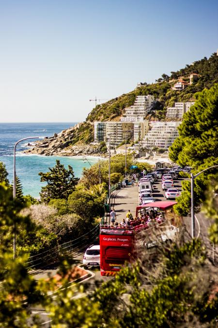 Cars on Road Near Blue Sea and Green Covered Mountains