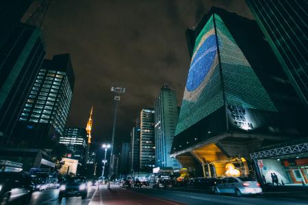 Cars Traveling on Road Between Buildings during Nighttime