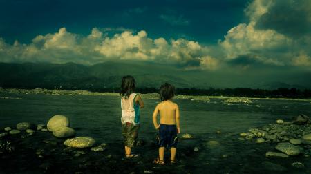 Child in White Tank Top Beside Child in Black Shorts Near Sea during Daytime