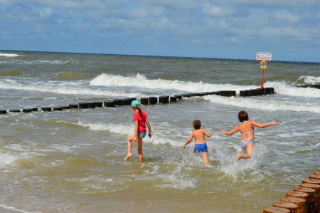 Children playing in a stormy sea near the breakwater. Baltic Sea