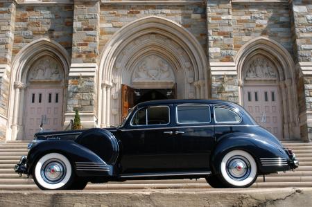 Classic Black Car Parked In Front Of Grey Concrete Building