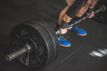 Close-up of a Person's Lower Body Holding Barbell