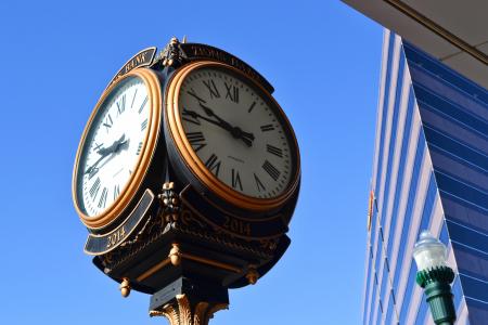Old forged street clock under a bright blue sky