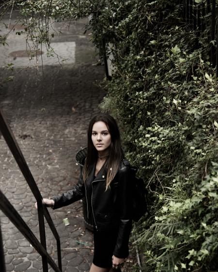 Close Up Photograph of Woman With Black Leather Jacket Standing Beside Stair Handle