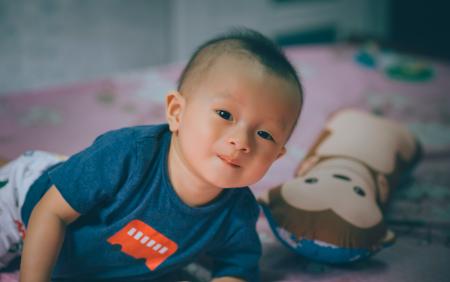 Close-Up Photography of Baby Lying on the Bed Near Bolster Pillow