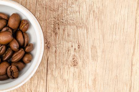 Coffee Beans on White Ceramic Bowl on Top of Brown Wooden Surface