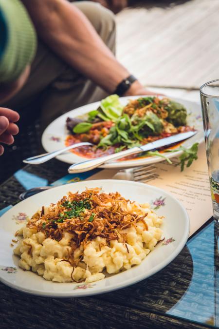 Cooked Pasta on White Ceramic Round Beside Vegetable Salad With Sauce