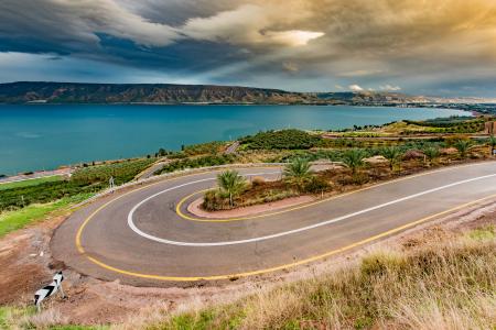 Curve Asphalt Road Near Blue Sea Under Gray Sky