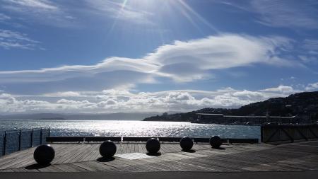 Five Balls Placed on Gray Wooden Platform Near Sea