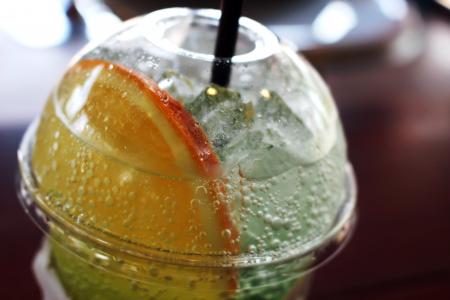 Fizzy soda drink with a slice of orange in a plastic cup