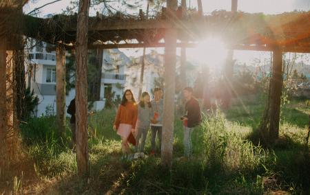 Four People Standing on Green Grass Near White Concrete House