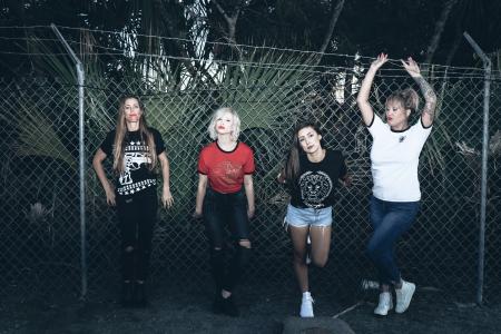 Four Women Leaning on Gray Steel Fence