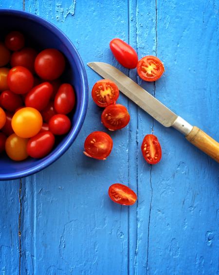 Freshly sliced organic cherry tomatoes on blue wooden background