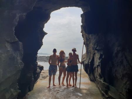Friends posing in the hole in the mountain on the beach