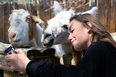 Funny girl takes a cute selfie with a goat on a farm