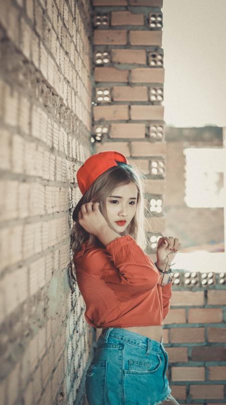 Girl in Orange Top Near Brown Concrete Brick