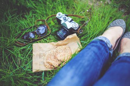 Girl resting on green grass with cookies and camera