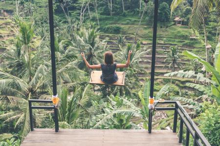Girl Swinging Above Green Trees at Daytime