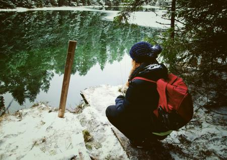 Girl Wearing Black Jacket Sitting In Front Of Calm Body Of Water