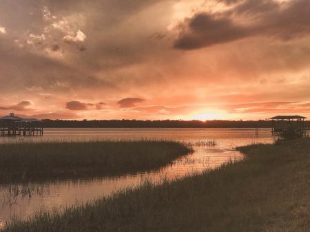 Grass Field Beside Body of Water during Sunset