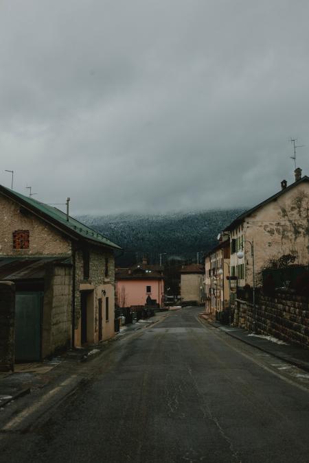 Gray Road Surrounded With Concrete Houses With Background of Dark Clouds