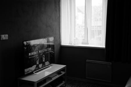 Gray Scale Photo of Flat Screen Tv on Top of Wooden Tv Rack