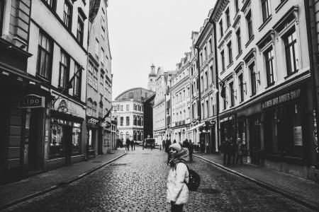 Grayscale Photo of a Woman Between Buildings Photo